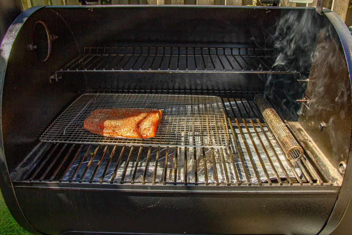 The salmon smoking on the traeger with a pellet tube smoker on the side.