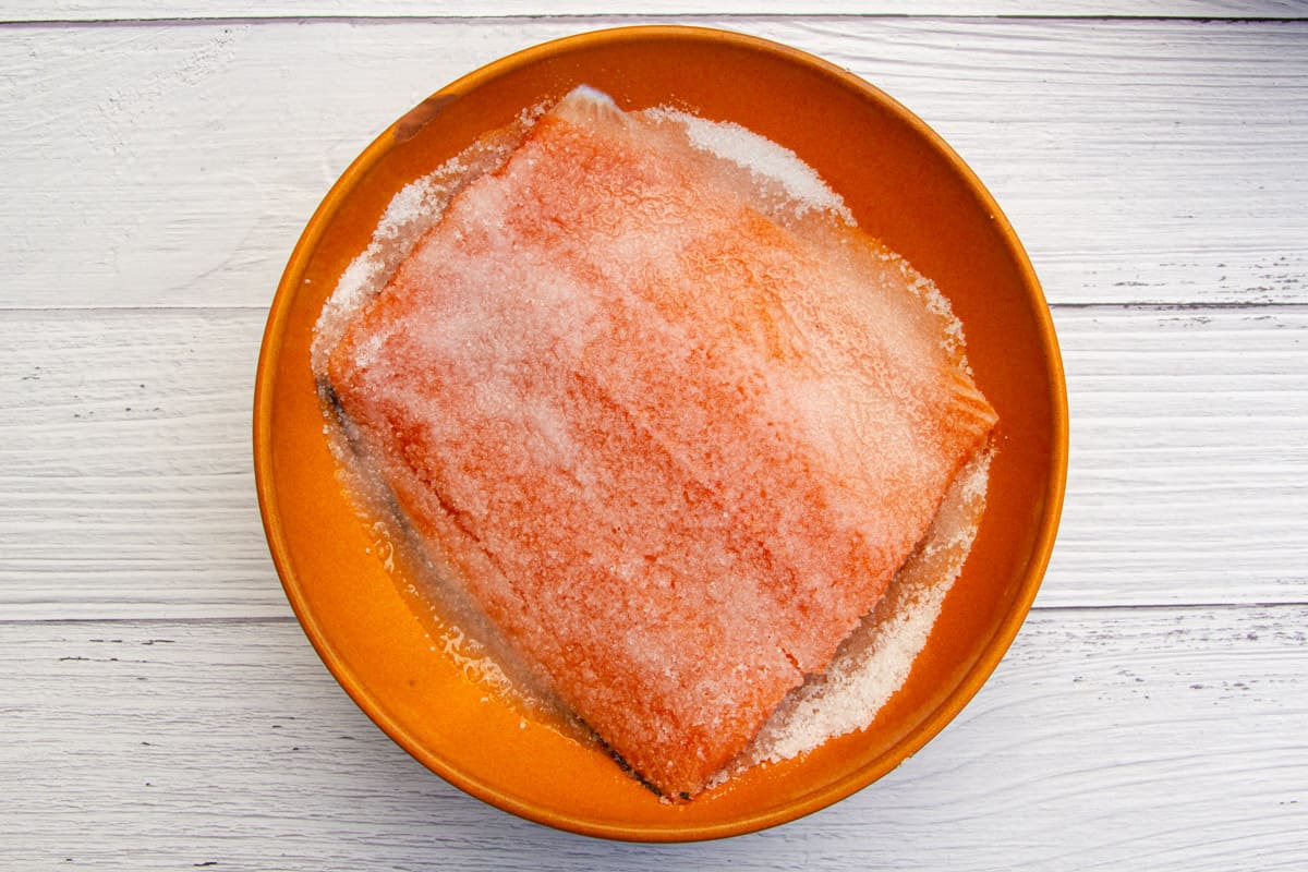 Covering the salmon filet in a salt and sugar cure.