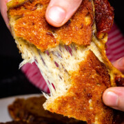 A close up shot of the smoked grilled cheese being pulled apart by two hands.