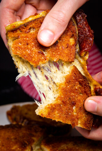 A close up shot of the smoked grilled cheese being pulled apart by two hands.