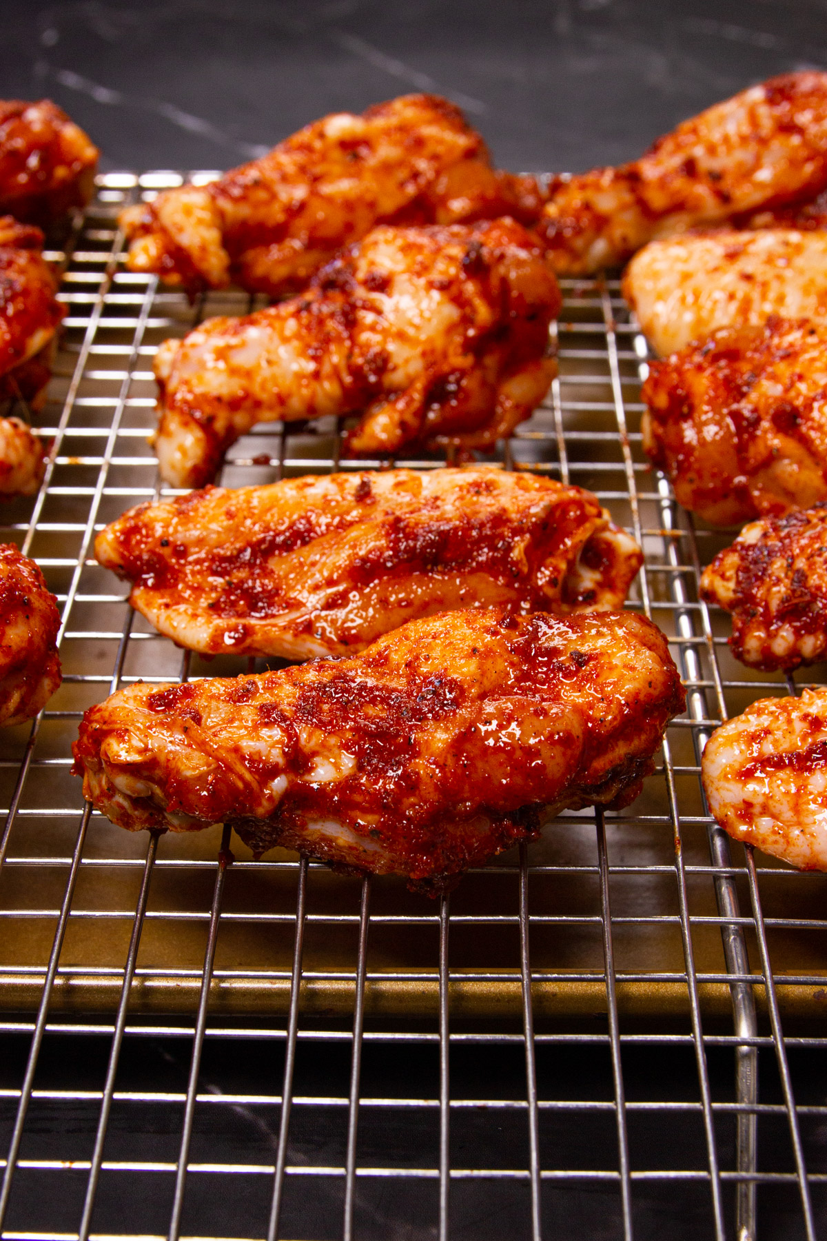 The wings drying on a resting rack with the spice rub.