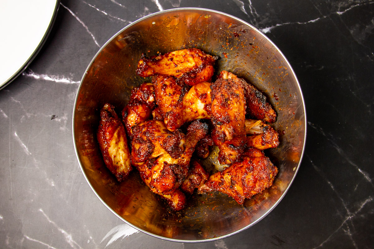 Tossing the wings in a bowl with butter and extra dry rub.