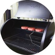 A traeger smoker with some burgers on it.