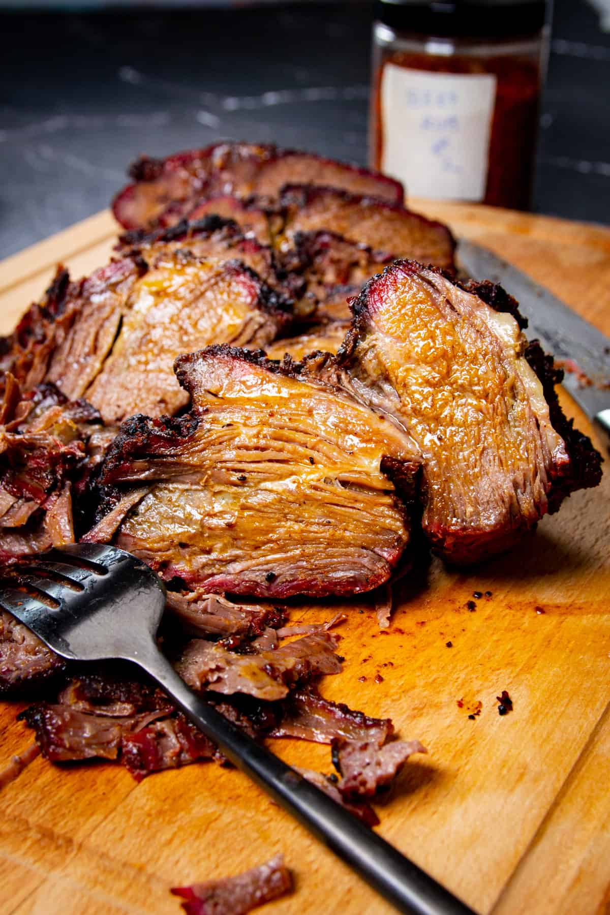 A close up shot of the poor mans brisket on a cutting board with a fork and spice rub in the background.