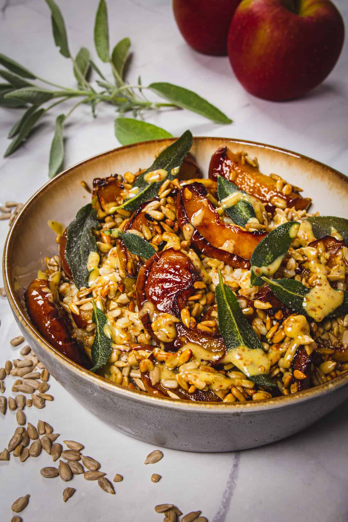 The spelt salad with fresh sage, apples and sunflower seeds around it.