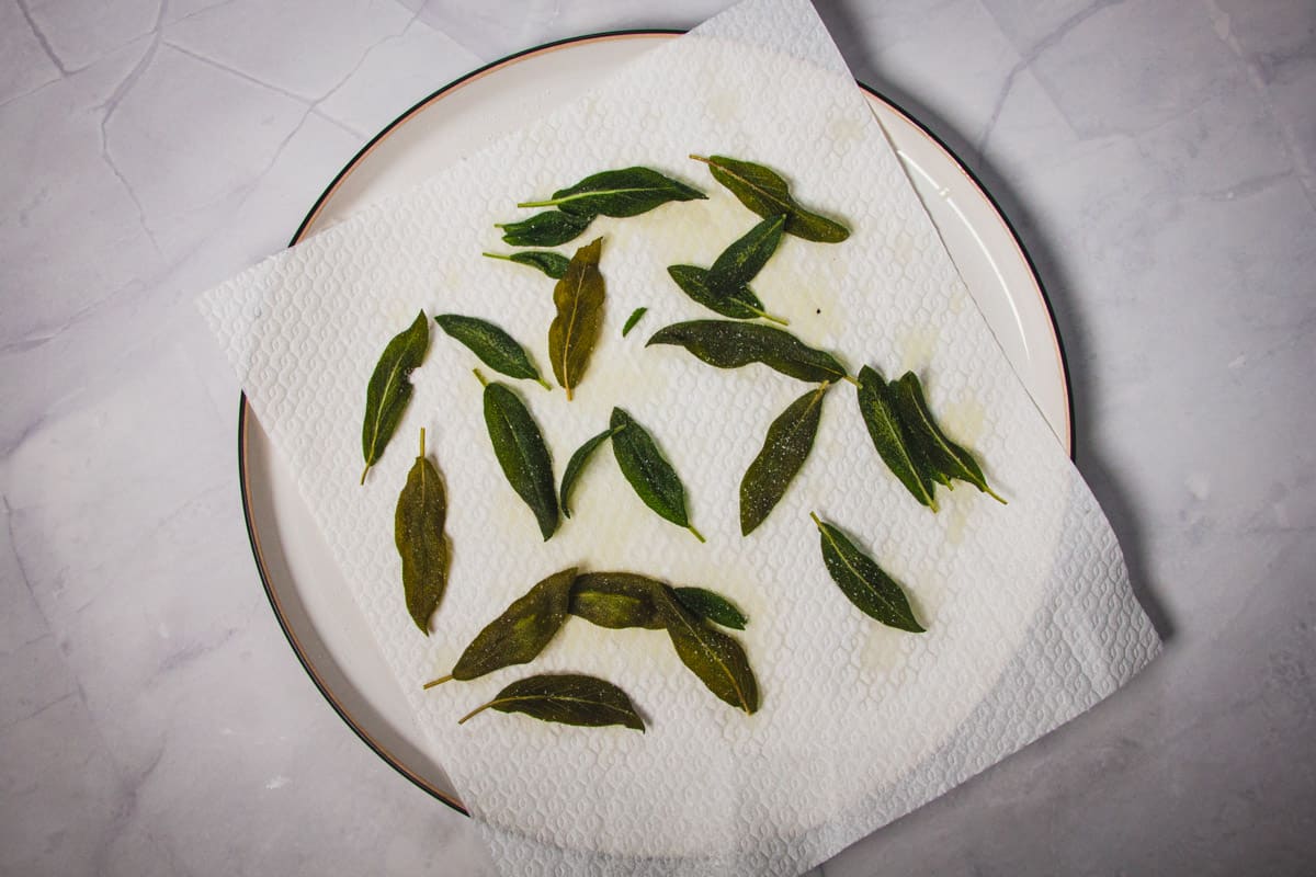 Crispy sage leaves on a plate with paper towel.